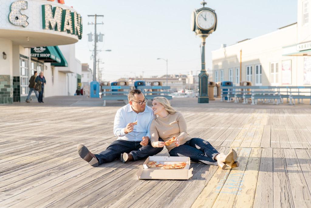 Couple eating pizza on the boardwalk for their maternity session