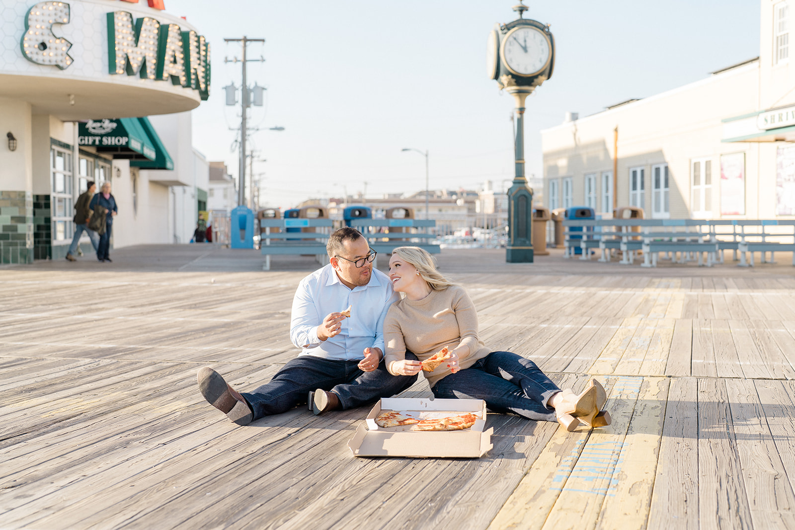Couple sitting on the boardwalk eating pizza
