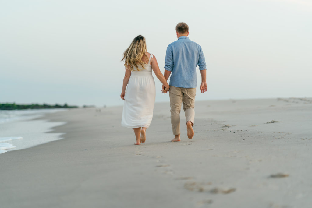 Couple walking on Cape May beach holding hands at sunrise