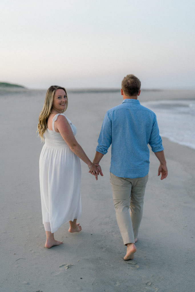 Couple walking on Cape May beach holding hands at sunrise