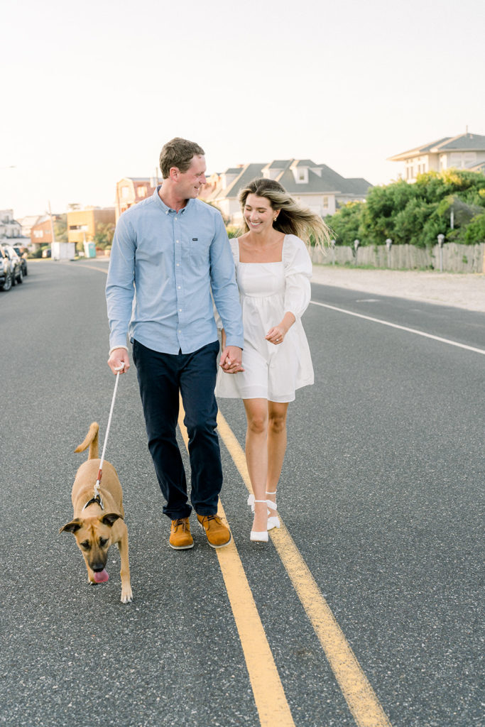 Couple walking their dog during Ocean City sunset engagement session