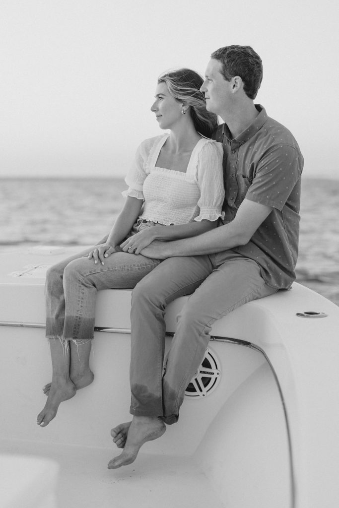 Couple sitting on boat during romantic engagement session in Ocean City, New Jersey