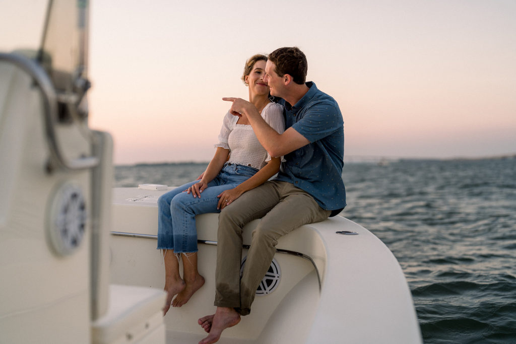 Couple sitting on boat during romantic engagement session, in Ocean City, New Jersey
