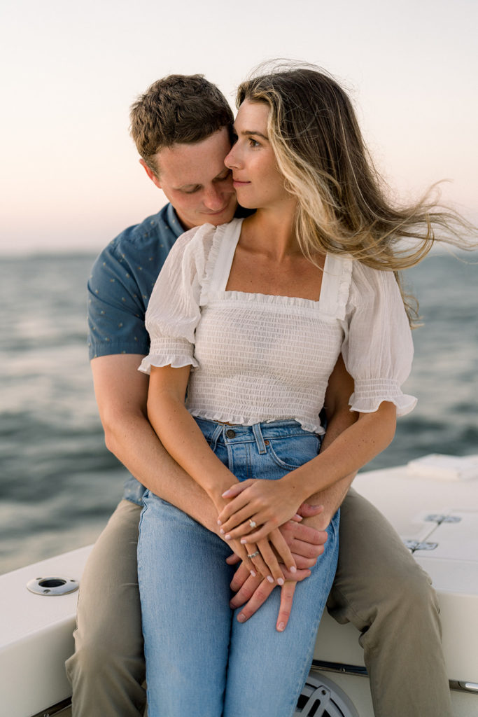 Couple hugging on boat during romantic engagement session in Ocean City, New Jersey