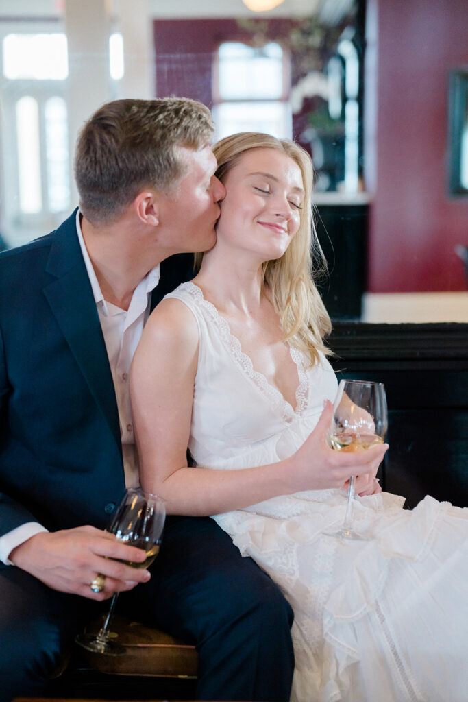 Couple laughing and drinking wine at Congress Hall in Cape May, New Jersey for their charming engagement session