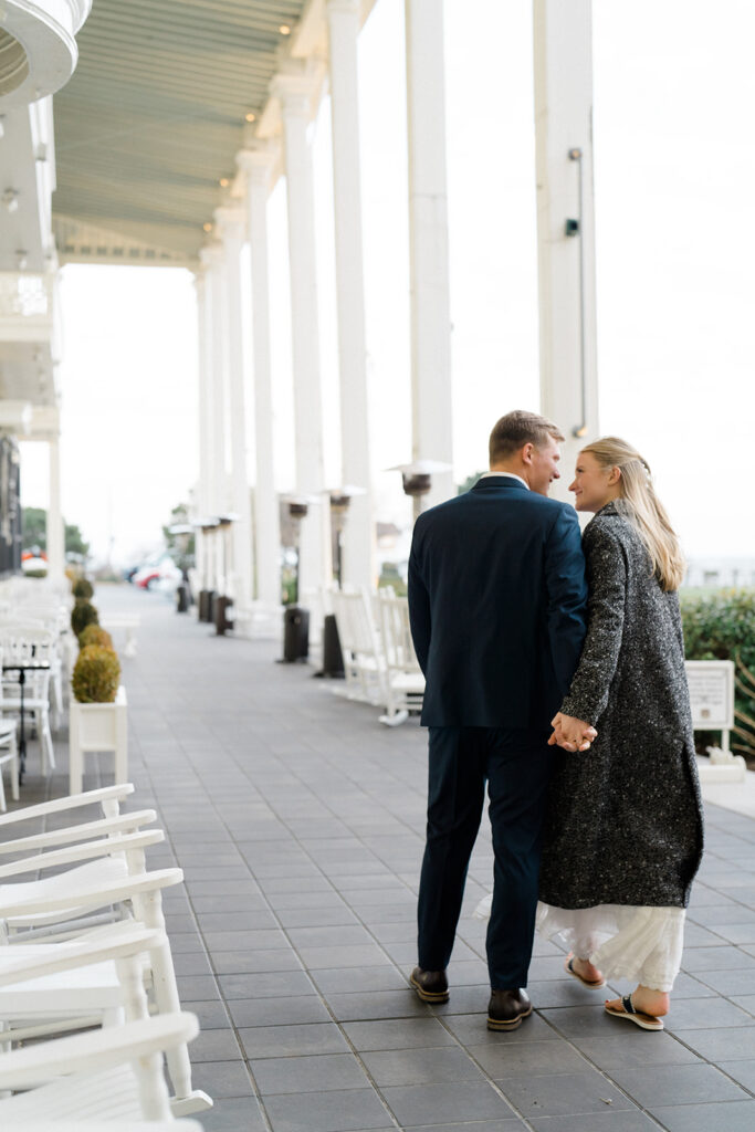 Newly engaged couple walking outside and holding hands in front of Congress Hall in Cape May, New Jersey for their charming engagement session