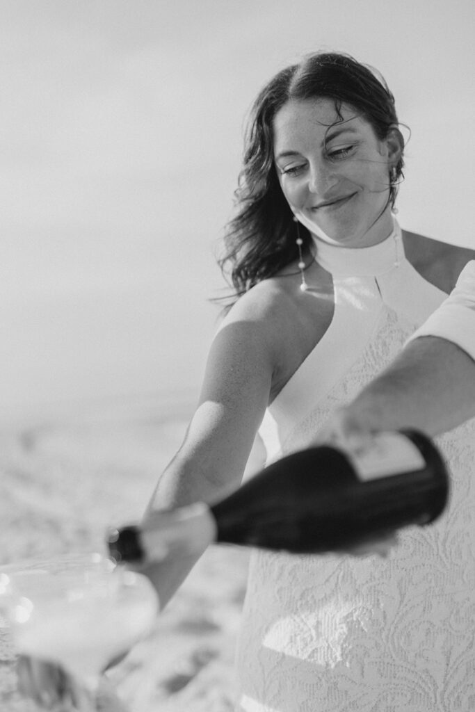 Engaged couple pouring champagne on the beach
