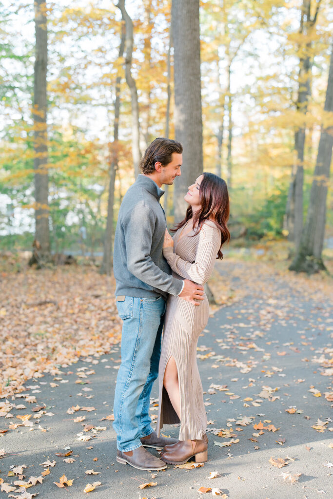Couple hugging during engagement session photos with colorful fall leaves