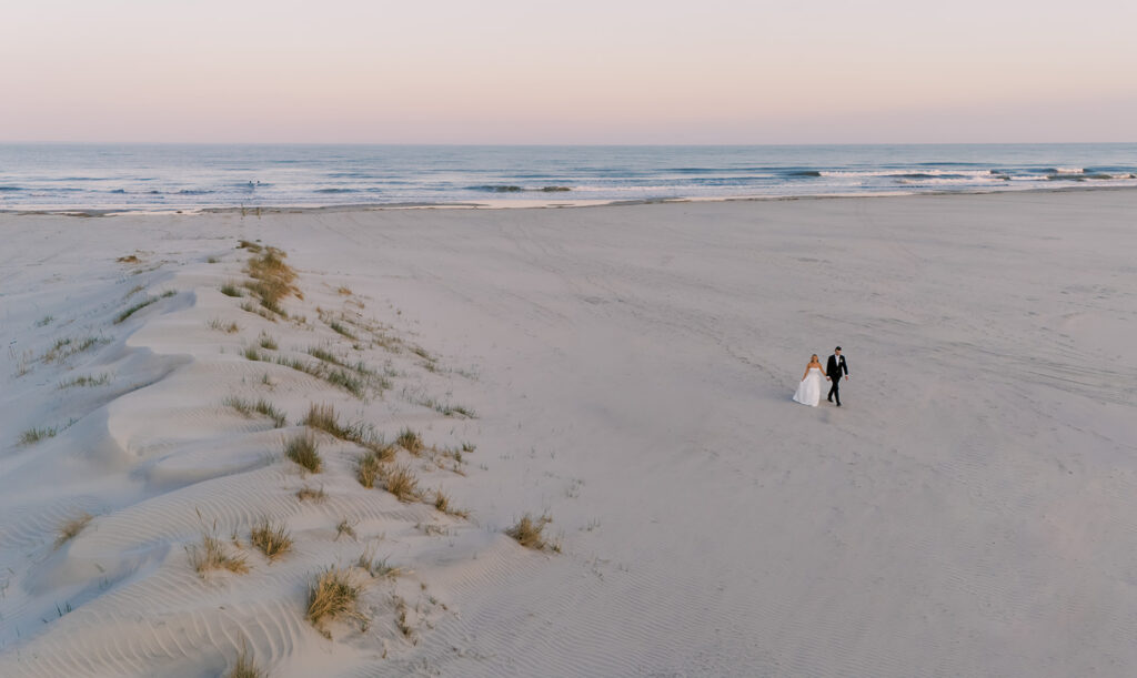 Bride and groom holding hands outside Icona Diamond Beach on their Cape May, NJ wedding day