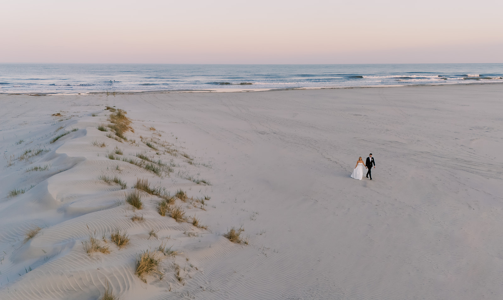 Bride and groom holding hands outside Icona Diamond Beach on their Cape May, NJ wedding day